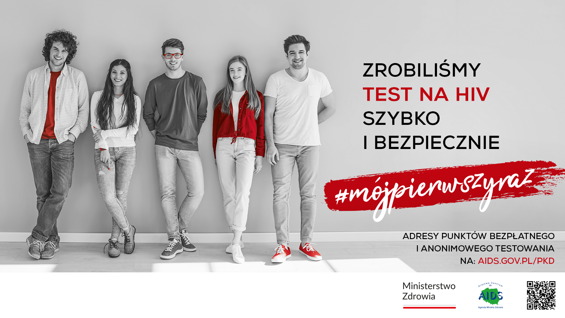Grupa uśmiechniętych młodych osób na czarno-białym zdjęciu z czerwonym hasłem: „Zrobiliśmy TEST NA HIV szybko i bezpiecznie” oraz #mójpierwszyraz.