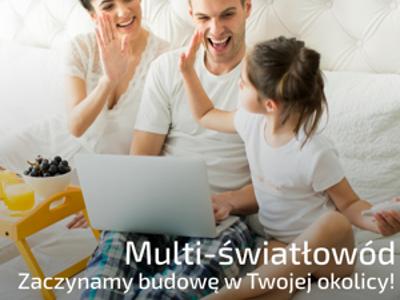 Rodzina z dzieckiem na łóżku korzysta z laptopa, dziewczynka przybija piątkę z tatą. Na dole info o światłowodzie i logotypy funduszy