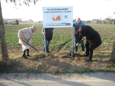 symboliczne posadowienie tablicy informacyjnej dotyczącej budowy przedszkola, Wójt wspólnie z Przewodnicząca Rady dokonują wkopania tablicy