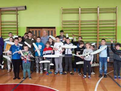 Zdjęcie grupowe członków klubu modelarskiego, dzieci trzymają modele samolotów