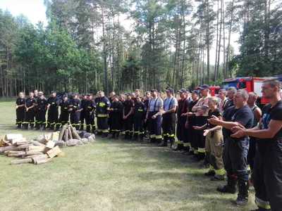 Ćwiczenia OSP, wszyscy uczestnicy ćwiczeń - strażacy stoją w grupie przy palenisku