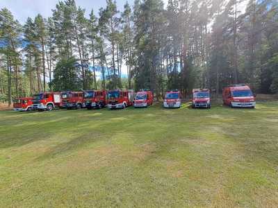 Ćwiczenia OSP, dziewięć wozów strażackich na tle drzew