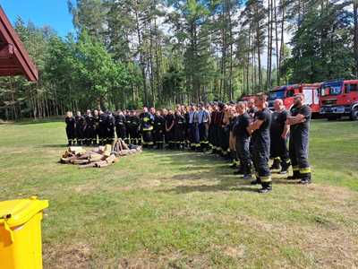 Ćwiczenia OSP, wszyscy uczestnicy ćwiczeń - strażacy stoją w grupie przy palenisku