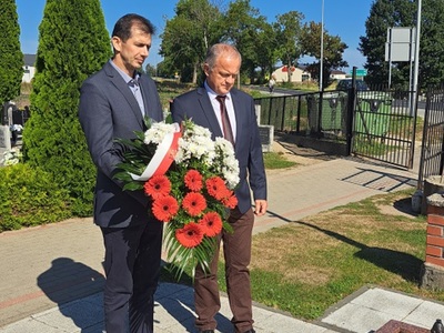 Wójt Gminy Mariusz Kosikowski i Przewodniczący Rady Damian Dominikowski składają wieniec z biało-czerwoną szarfą, cmentarz w Warlubiu