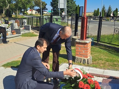 Wójt Gminy Mariusz Kosikowski i Przewodniczący Rady Damian Dominikowski składają wieniec z biało-czerwoną szarfą, cmentarz w Warlubiu