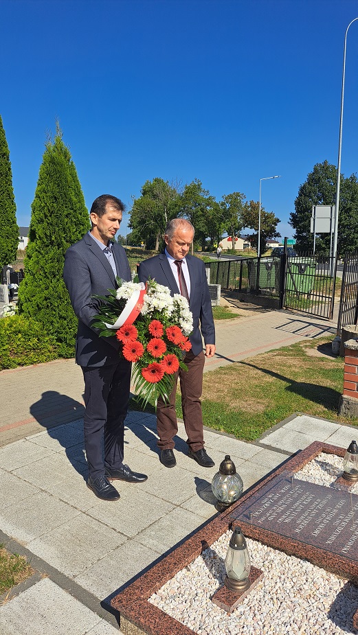 Wójt Gminy Mariusz Kosikowski i Przewodniczący Rady Damian Dominikowski składają wieniec z biało-czerwoną szarfą, cmentarz w Warlubiu