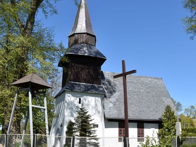Zdjęcie przedstawia kościół w Karwicach, krzyż i dzwonnicę. 