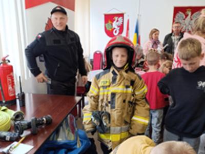 Dzieci przymierzają kombinezon strażacki.