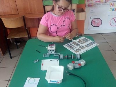 Zdjęcie przedstawia wychowankę Placówki Wsparcia Dziennego w Laskach podczas składania robota.
