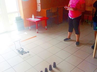 Zdjęcie przedstawia dziewczynkę, która steruje robotem za pomocą tableta. 