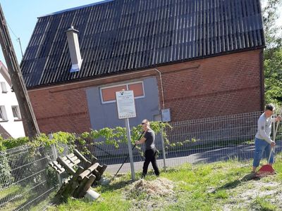 Zdjęcie przedstawia dwóch chłopców porządkujących teren przy świetlicy w Przystawach.