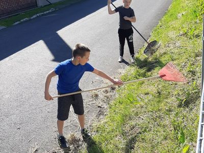 Zdjęcie przedstawia dwóch chłopców porządkujących teren przy świetlicy w Przystawach.