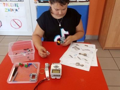 Zdjęcie przedstawia wychowankę Placówki Wsparcia Dziennego w Laskach, która konstruuje robot miotający. 