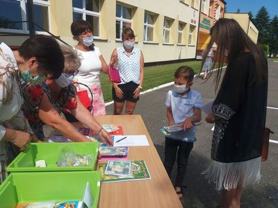 Zdjęcie przedstawia wychowawczynie z przedszkola w Ostrowcu, dziewczynkę z opiekunem odbierającą pamiątkowe dyplomy. 