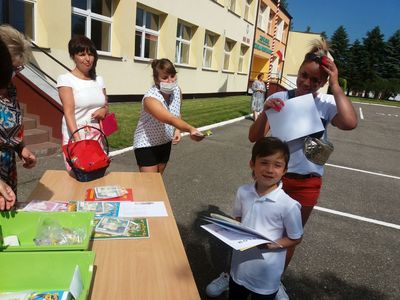 Zdjęcie przedstawia wychowawczynie z przedszkola w Ostrowcu, chłopca z opiekunką odbierającego pamiątkowe dyplomy. 