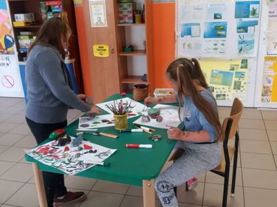 Zdjęcie ukazuje dwie dziewczynki z Placówki Wsparcia Dziennego w Laskach malujące kamienie.
