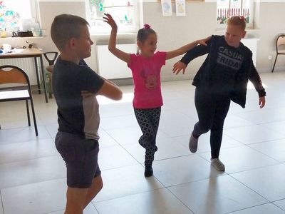 Zdjęcie przedstawia dzieci w tańcu podczas zajęć dziennikarsko - teatralnych na sali w Kusiach.