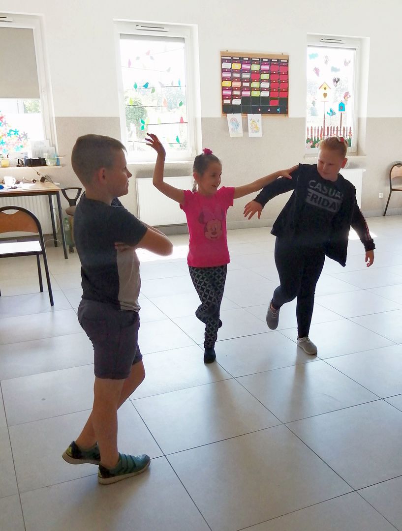 Zdjęcie przedstawia dzieci w tańcu podczas zajęć dziennikarsko - teatralnych na sali w Kusiach.