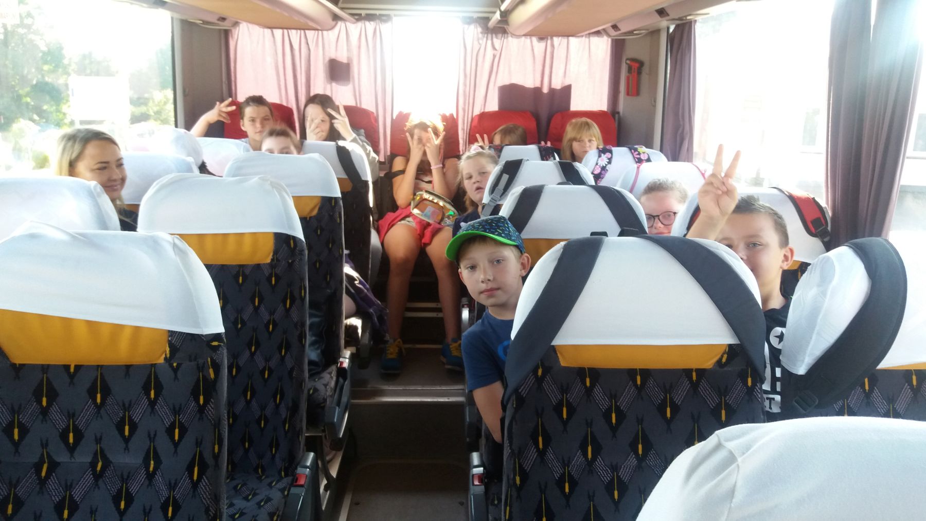 Zdjęcie przedstawia dzieci z wychowawczynią w autobusie.