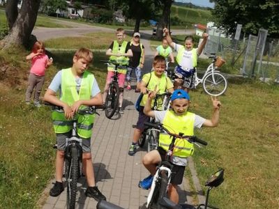 Zdjęcie przedstawia dzieci z Placówki Wsparcia Dziennego w Kusicach wraz z opiekunami podczas rajdu rowerowego do Sierakowa,