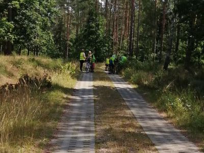 Zdjęcie przedstawia leśną dróżkę i dzieci z Kusic w tle. 