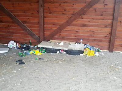 Zdjęcie przedstawia zaśmiecony teren w okolicy wiaty na boisku wiejskim w Malechówku. 