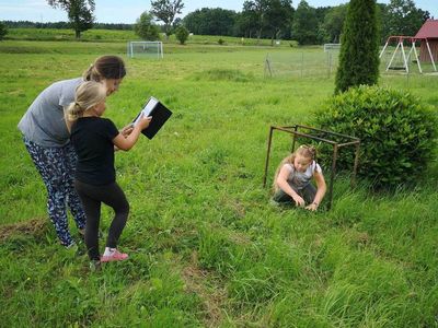 Zdjęcie przedstawia wychowanków Placówki Wsparcia Dziennego w Kusicach: dziewczynkę pozującą do zdjęcia oraz inną osobę wykonującą fotografię przy pomocy wychowawcy.  