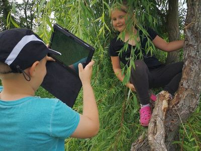 Zdjęcie przedstawia wychowanka Placówki Wsparcia Dziennego w Kusicach, wykonującego zdjęcie i dziewczynkę pozującą do zdjęcia.