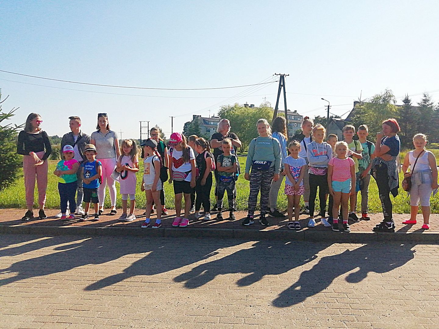 Zdjęcie przedstawia grupę wychowanków Placówki Wsparcia Dziennego z Kusic wraz z opiekunami przed parkiem rozrywki Pomerania.