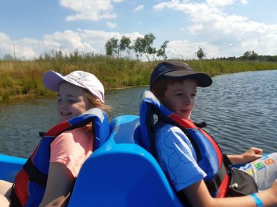 Zdjęcie przedstawia wychowanków Placówki Wsparcia Dziennego z Niemicy podczas przejażdżki rowerkami wodnymi w parku rozrywki Pomerania. 