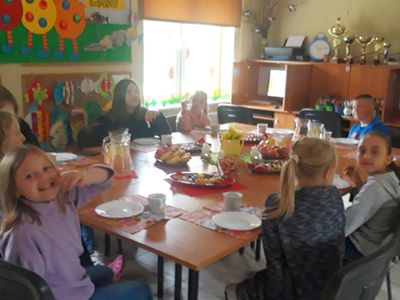 Zdjęcie przedstawia wychowanków Placówki Wsparcia Dziennego z Kosierzewa jedzących pizzę przy stole w świetlicy.