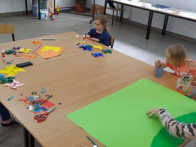 Zdjęcie przedstawia wychowanków Placówki Wsparcia Dziennego z Gorzycy oraz mamę jednego z dzieci, którzy przygotowują wspólnie  kolorowe wiatraki w świetlicy.