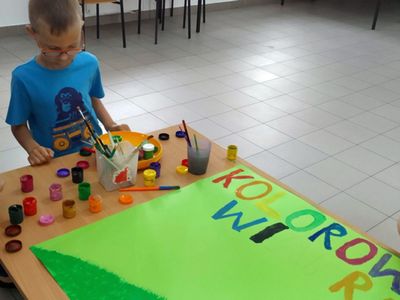 Zdjęcie przedstawia wychowanków Placówki Wsparcia Dziennego z Gorzycy, którzy przygotowują kolorowy plakat przy użyciu farb. 