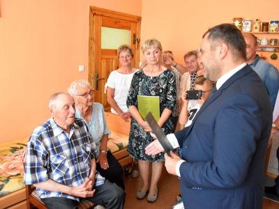 Zdjęcie przedstawia Jubilata Stanisława Filipiaka z Pękanina z rodzinką i wójta Radosława Nowakowskiego odczytującego list gratulacyjny.
