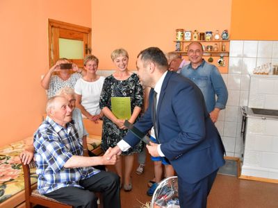 Zdjęcie przedstawia Jubilata Stanisława Filipiaka z Pękanina z rodzinką i wójta Radosława Nowakowskiego odczytującego list gratulacyjny.