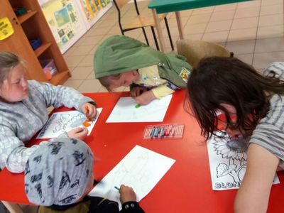 Zdjęcie przedstawia wychowanków Placówki Wsparcia Dziennego z Lasek, którzy kolorują przygotowane karty roślin. 