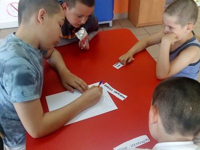 Zdjęcie przedstawia wychowanków Placówki Wsparcia Dziennego z Lasek przy stole podczas zajęć teatralno - dziennikarskich.