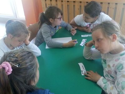 Zdjęcie przedstawia wychowanków Placówki Wsparcia Dziennego z Lasek przy stole podczas zajęć teatralno - dziennikarskich.