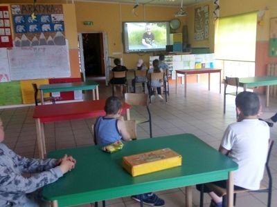 Zdjęcie przedstawia wychowanków Placówki Wsparcia Dziennego z Lasek przy stole podczas zajęć teatralno - dziennikarskich w świetlicy. 