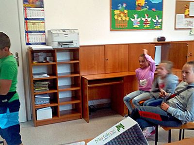 Zdjęcie przedstawia wychowanków Placówki Wsparcia Dziennego z Ostrowca, jednego chłopca przy tablicy oraz troje dzieci za nim na krzesłach. 