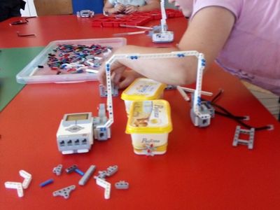 Zdjęcie przedstawia dzieci z PWD Laski budujące przejazd kolejowy z klocków lego.