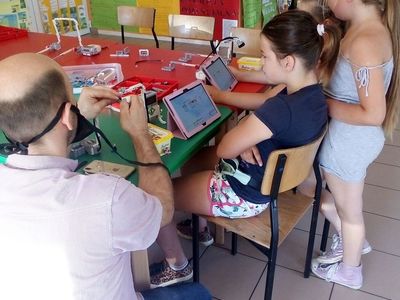 Zdjęcie przedstawia dzieci z PWD z Lasek,które programują roboty na tabletach.