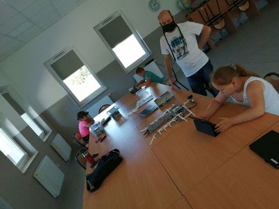 Zdjęcie przedstawia dzieci, które robią maszynę do składania koszulek podczas zajęć robotyki w PWD Kusice.
