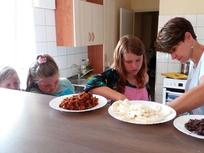 Zdjęcie przedstawia wychowanków PWD Laski wraz z Panią dietetyk podczas przygotowywania zapiekanki na zajęciach kulinarnych.