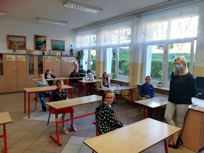 Zdjęcie przedstawia uczniów ze szkoły w Lejkowie z nauczycielem, którzy znajdują się w klasie. 