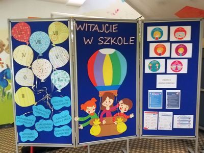 Zdjęcie przedstawia tablicę z materiałami plastycznymi, która nawiązuje do powitania uczniów w szkole. 