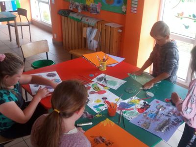 Zdjęcie przedstawia grupkę dzieci z PWD Laski podczas wykonywania prac plastycznych.