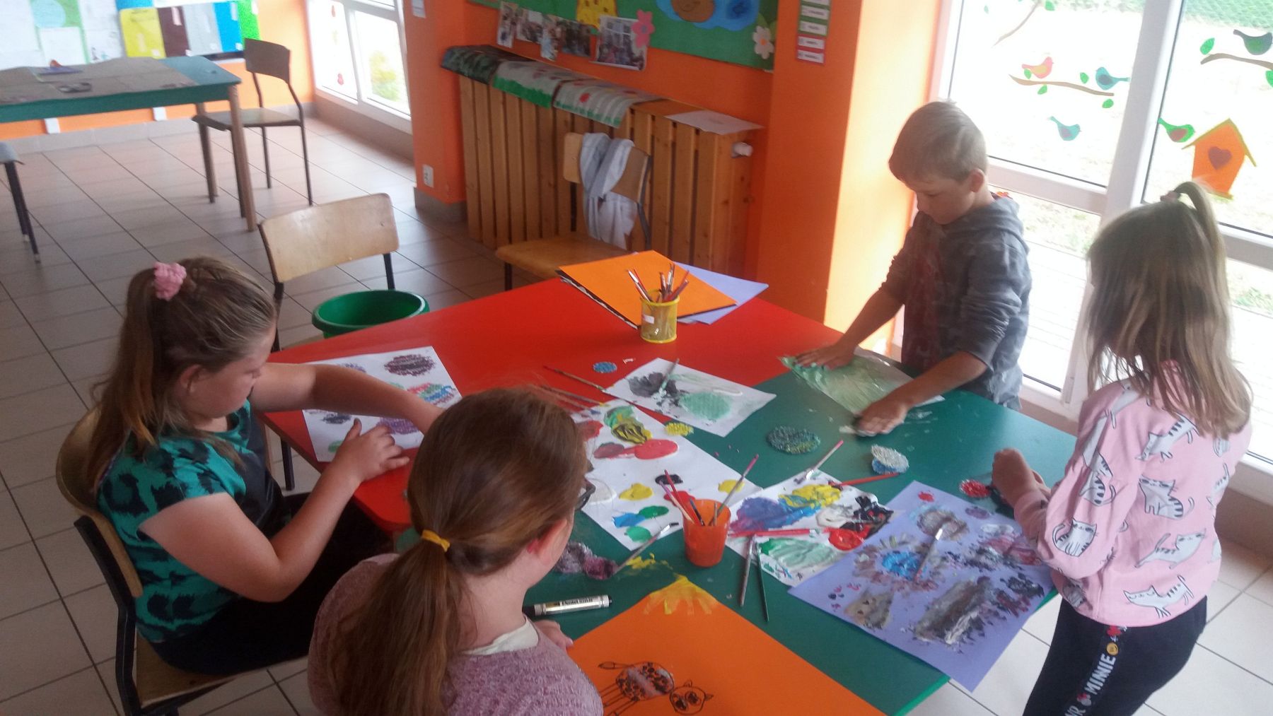 Zdjęcie przedstawia grupkę dzieci z PWD Laski podczas wykonywania prac plastycznych.