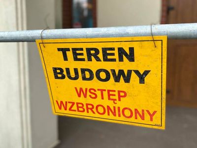 Zdjęcie przedstawia tabliczkę z napisem Teren Budowy Wstęp Wzbroniony przed modernizowanym domem przedpogrzebowym w Malechowie. 