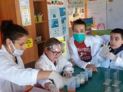 Zdjęcie przedstawia dzieci z PWD w Laskach uczestniczących w zajęciach fizyczno-chemicznych z elementami matematyki podczas przygotowywania doświadczenia.